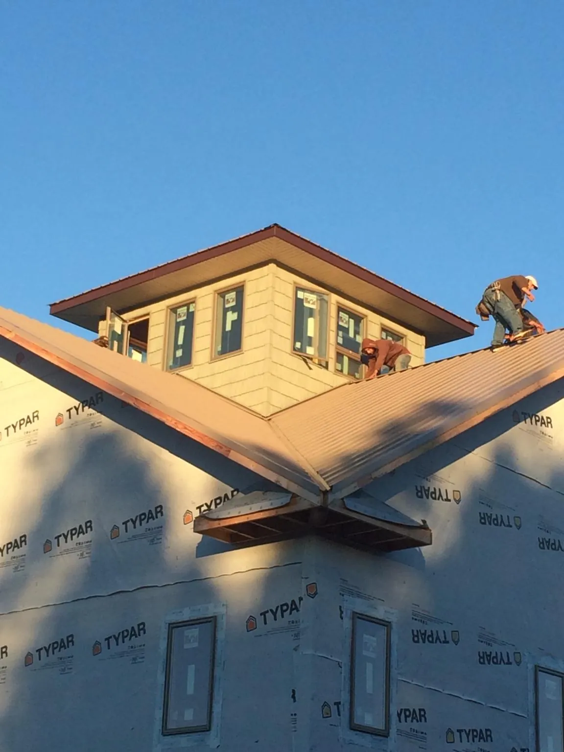 Roofers working around a rooftop cupola on a new metal roof at sunset — Roof Waterproofing in Newbury by Roofing Brothers